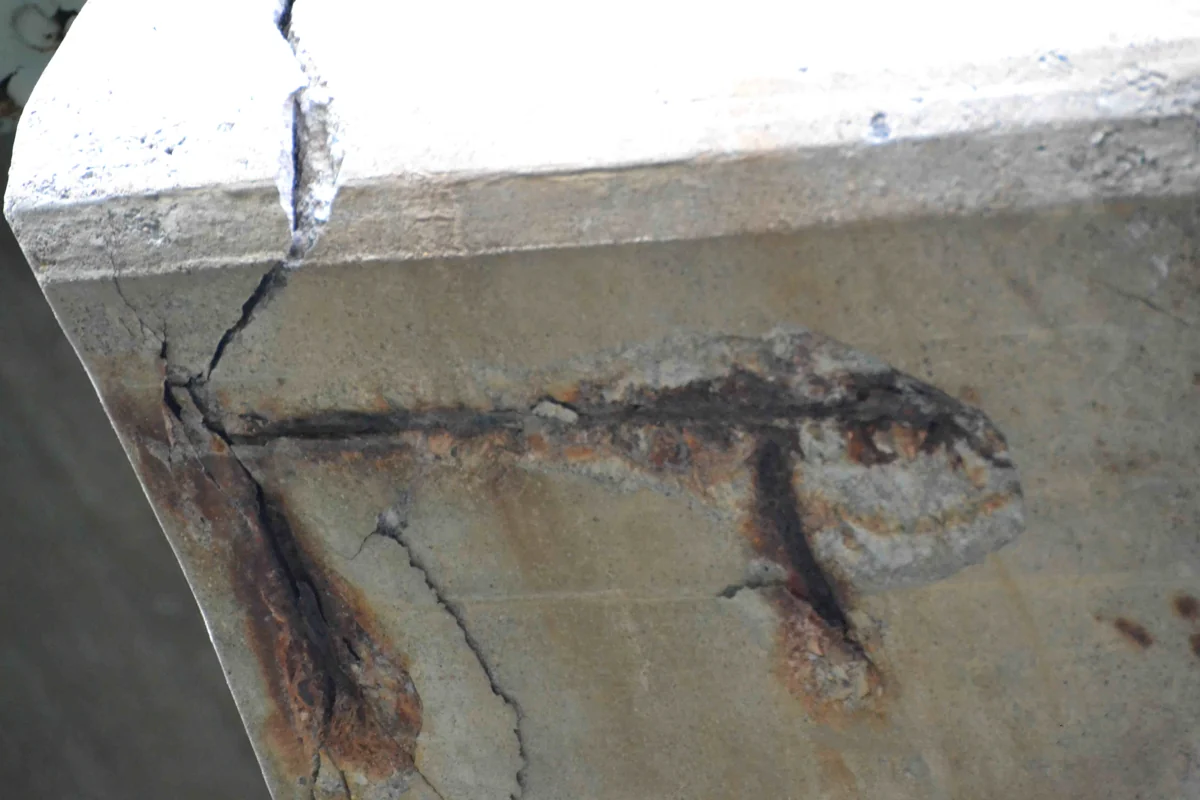 Cracked and spalled concrete with exposed rusted reinforcement beneath a QEW bridge in Niagara Falls, photographed in 2012